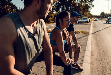 Sticker - Group of sports people stretching muscles before running in city street in morning.