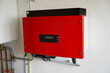 red solar power inverter mounted on a white wall. Sustainable energy production. Green power. Groene stroom met omvormer.