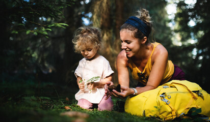 Wall Mural - happy mother with small daughter outdoors in summer nature, resting in forest.