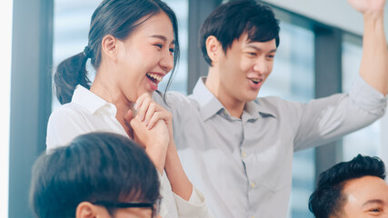 Millennial group of young businesspeople Asia businessman and businesswoman celebrate giving five after dealing feeling happy and signing contract or agreement at meeting room in small modern office.