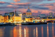 Cityscape of London at dusk, view of the famous Saint Pauls Cathedral ans boats on the River Thames illuminated at sunset.