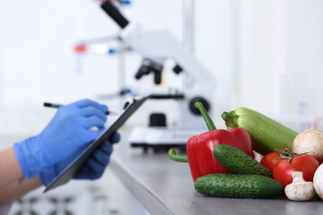 Wall Mural - fresh vegetables on table, scientist proceeding quality control in laboratory
