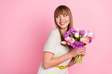 Poster - Portrait of attractive cheerful glad girl holding in hands flowers looking aside copy space isolated over pink pastel color background