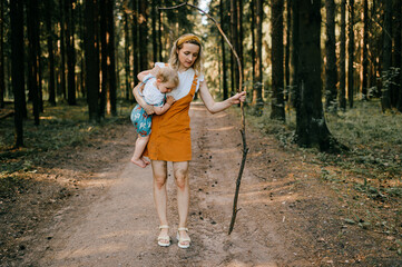 Wall Mural - Young mother with stick holding her son in the forest