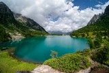 Fototapeta Góry - Summer sunny day in nature. Panoramic view of Aviolo lake in Adamello park, Italy. Vivid turquoise color water in alpine mountain lake sandwiched between mountains.