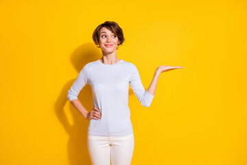 Poster - Photo portrait of woman holding blank space in hand isolated on bright yellow colored background