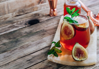 Wall Mural - Cold lemonade cocktail with figs on rustic wooden background