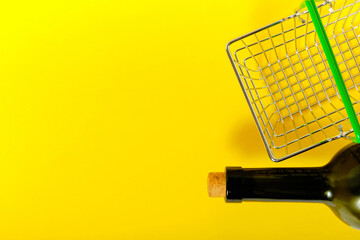 Bottle of wine and a shopping basket on a yellow background.