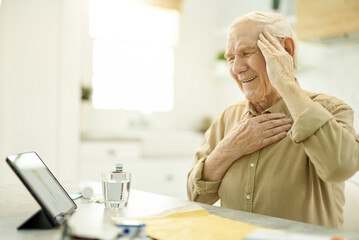 Wall Mural - Elderly man in pain consulting a doctor online