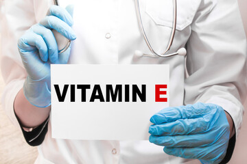 The doctor's blue - gloved hands show the word VITAMIN E - . a gloved hand on a white background. Medical concept. the medicine