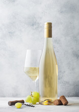 Glass And Bottle Of Summer White Wine With Grapes, Corks And Corkscrew On Light Background.
