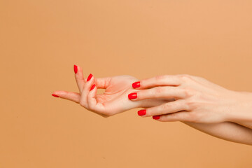 Wall Mural - Close up photo of woman enjoying her beauty. Attractive hands with manicure of young woman isolated on beige background.