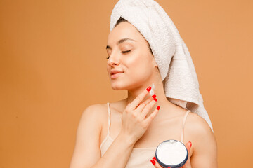 Wall Mural - Photo of attractive young woman in underwear and towel, puts nutrition cream on her skin, isolated on beige background. Sport, fitness, diet, nutrition and health care concept