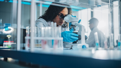 Wall Mural - medical science laboratory: portrait of beautiful black scientist looking under microscope does anal