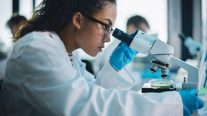 Wall Mural - medical science laboratory: beautiful black scientist looking under microscope does analysis of test