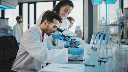 Wall Mural - modern medical research laboratory: portrait of latin and black young scientists using microscope, d