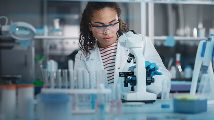 Wall Mural - medical science laboratory: portrait of beautiful black scientist using microscope, does analysis of