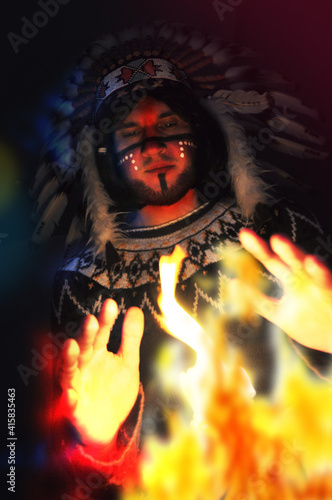 Plakat Portrait of a young handsome guy in a hat with a feather of the chief of the Indians. Fire and man - portrait