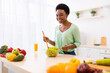 © Prostock-studio - African Female Cooking In Kitchen Preparing Vegetable Salad For Lunch