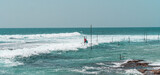 Fototapeta Fototapety z morzem do Twojej sypialni - Tropikalna plaża z palmami, niebieski ocean z falami oraz kije rybackie.
