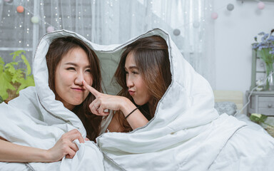 Two women laying down under blanket at home