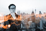Fototapeta Nowy Jork - A young eastern handsome trader and stock market analyst in suit dreaming about market behavior and forecast in crisis. Trading at corporate finance fund. Forex chart. Kuala Lumpur. Double exposure.