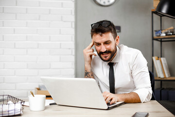 Wall Mural - Young businessman using laptop in his office. Happy man working on computer at his workplace..