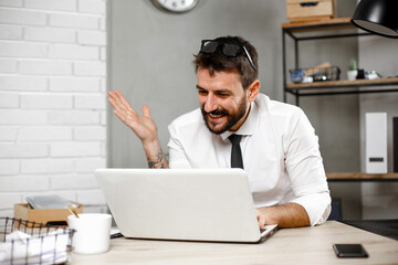 Wall Mural - Young businessman using laptop in his office. Happy man working on computer at his workplace..