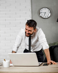 Wall Mural - Young businessman using laptop in his office. Happy man working on computer at his workplace..