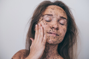 Close-up portrait of woman applying coffee mask for cleansing, wants to look rejuvenated and healthy, shows healthy body after spa procedure