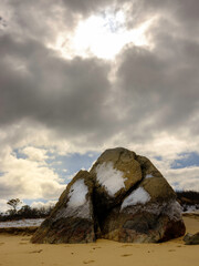 Wall Mural - Triangle Shaped Giant Glacial  Rock Covered with Snow on Cloudy Beach