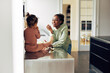 © Flamingo Images - Smiling mom and her little daughter eating fruit at home