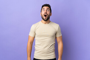 Canvas Print - Young handsome man with beard over isolated background looking up and with surprised expression