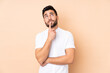 © luismolinero - Caucasian handsome man isolated on beige background having doubts while looking up