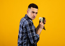 Young Man With Wallet Full Of Money Being Greedy Over His Wealth On Orange Studio Background