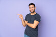 © luismolinero - Caucasian handsome man pointing finger to the side over isolated purple background