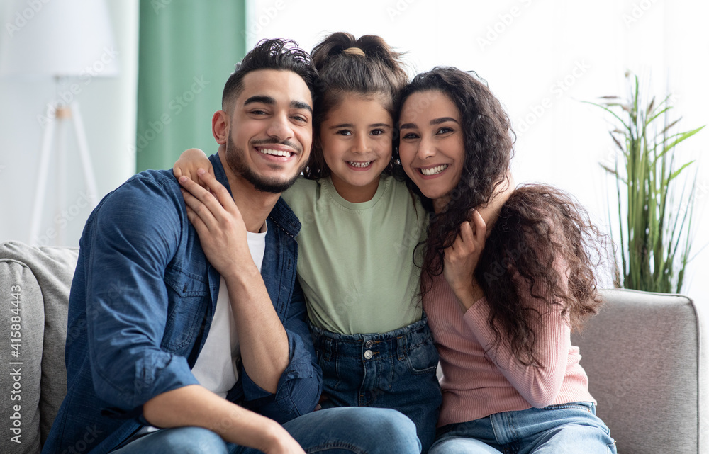 Happy Family Portrait. Smiling arabic parents and their little daughter posing together - obrazy, fototapety, plakaty 