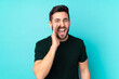 © luismolinero - Caucasian handsome man isolated on blue background shouting with mouth wide open