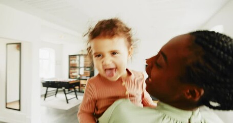 Wall Mural - Loving young African mother playing with her laughing little daughter in her arms in their kitchen at home