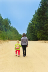 Little tourists go on road. Girls travellers walk on the forest path