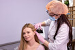 © alfa27 - woman client at trichologist office get injections in head skin by professional. doctor's hands holding disposable syringe under patient's head. Porcedure against hair loss and for skin health.