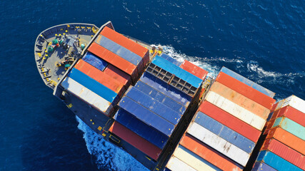 Aerial drone photo of colourful truck size container tanker ship cruising deep blue sea near commercial port of Piraeus, Attica, Greece