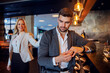 © Dusan Petkovic - Unfaithful middle-aged man sitting in the bar of a fancy hotel and taking off his wedding ring. In the background is a woman who is seducing him.
