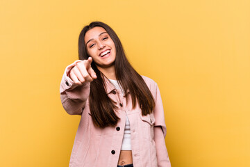 Young Indian woman isolated on yellow background pointing to front with fingers.