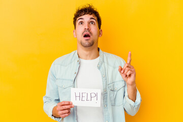 Wall Mural - Young caucasian man holding a help placard isolated pointing upside with opened mouth.