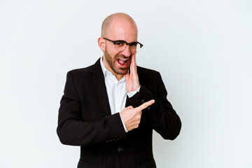 Young business caucasian bald man isolated on blue background saying a gossip, pointing to side reporting something.