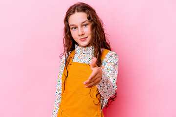 Wall Mural - Little caucasian girl isolated on pink background stretching hand at camera in greeting gesture.