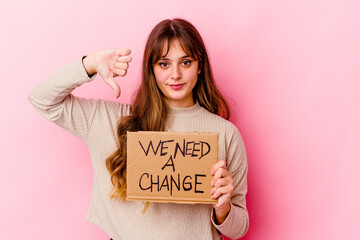 Wall Mural - Young caucasian woman holding a We need a change placard isolated showing a dislike gesture, thumbs down. Disagreement concept.