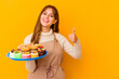Young pastry chef woman isolated on yellow background smiling and raising thumb up