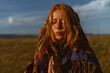 © mnelen.com - Against the blue sky stands folded in prayer hands with a cape-covered head red-haired girl with freckles and tan on her face. High quality photo